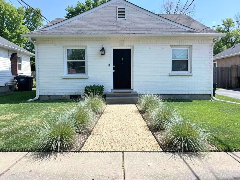 AI-edited version of the same image: a straight light tan pea gravel path with thin black edging from the sidewalk to the steps, and clumps of silvery-green ornamental grass on both sides