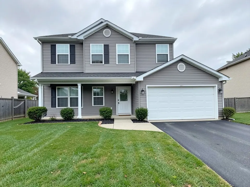 AI-generated example: a grey two-story house with black shutters, a white two-car garage door, a covered porch with a glass front door, small round shrubs along the front, a black asphalt driveway on the right, a wooden fence at the left and a mown lawn under an overcast sky