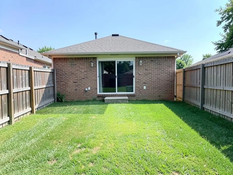 AI-generated example: the back of a red-brick one-story house with a sliding glass door and a small concrete step, wooden privacy fences on both sides, a shrub at the left corner of the house and a plain green lawn in front