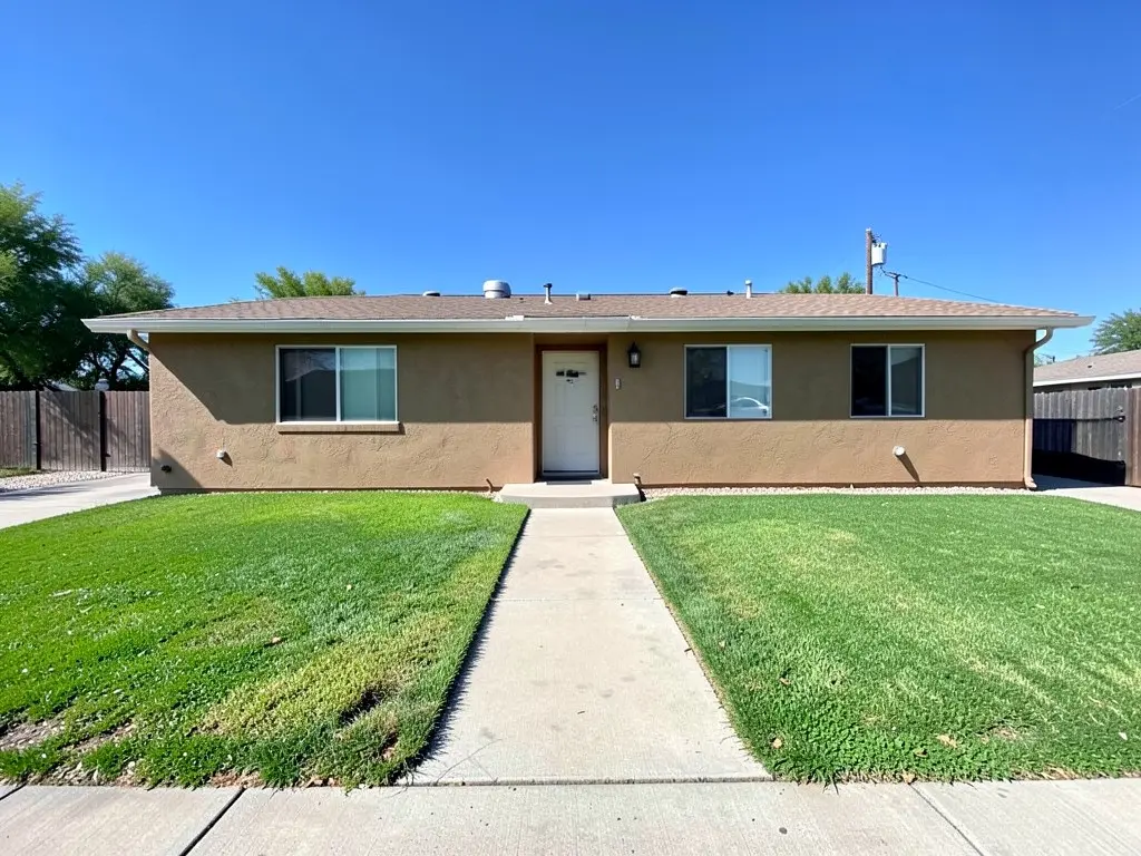 Tan stucco ranch house with a plain green grass lawn and a straight concrete walkway