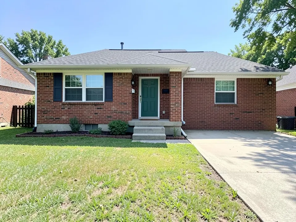 AI-generated example: a single-storey red brick house with a green front door and dark blue shutters, concrete front steps, a driveway on the right and a plain grass front lawn with a thin mulch strip at the foundation